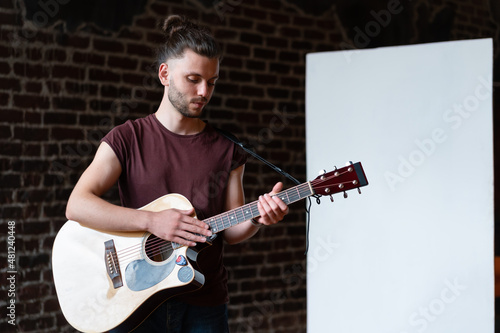 Man with acoustic guitar standing near whiteboard Music school concept