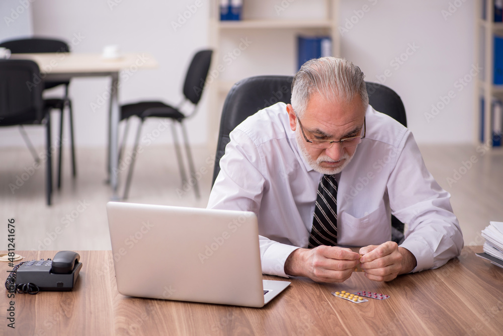 Aged male employee suffering at workplace Aged male employee suffering at workplace