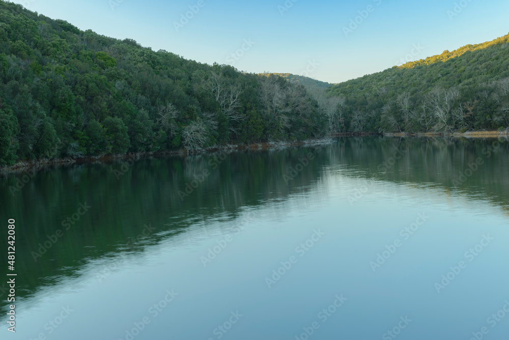Scenic landscape on a sunny day on the lake with the reflection of the trees and the sky in the water. Bicocchi lake, Montioni Natural Park, Tuscany Italy Scenic landscape on a sunny day on the lake with the reflection of the trees and the sky in the water. Bicocchi lake, Montioni Natural Park, Tuscany Italy
