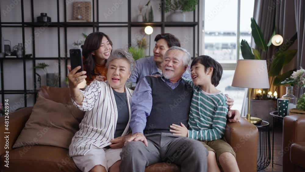 Asian big family look talk to camera and waving hand at home. video calling communicate in online chat Asian big family look talk to camera and waving hand at home. video calling communicate in online chat