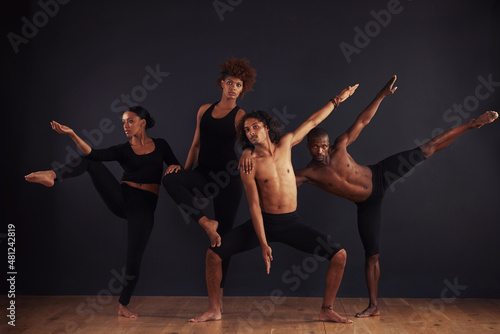Fototapeta Naklejka Na Ścianę i Meble -  Powerful individuals. A group of dancers performing a dramatic pose in front of a dark background.