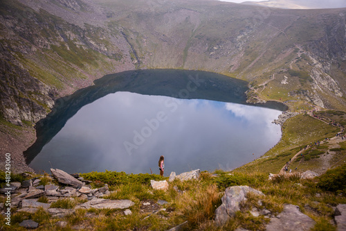 Little girl silhouette standing by a huge mist lake on Rila hiking trail in Bulgaria. Stunning nature landscape. High quality photo