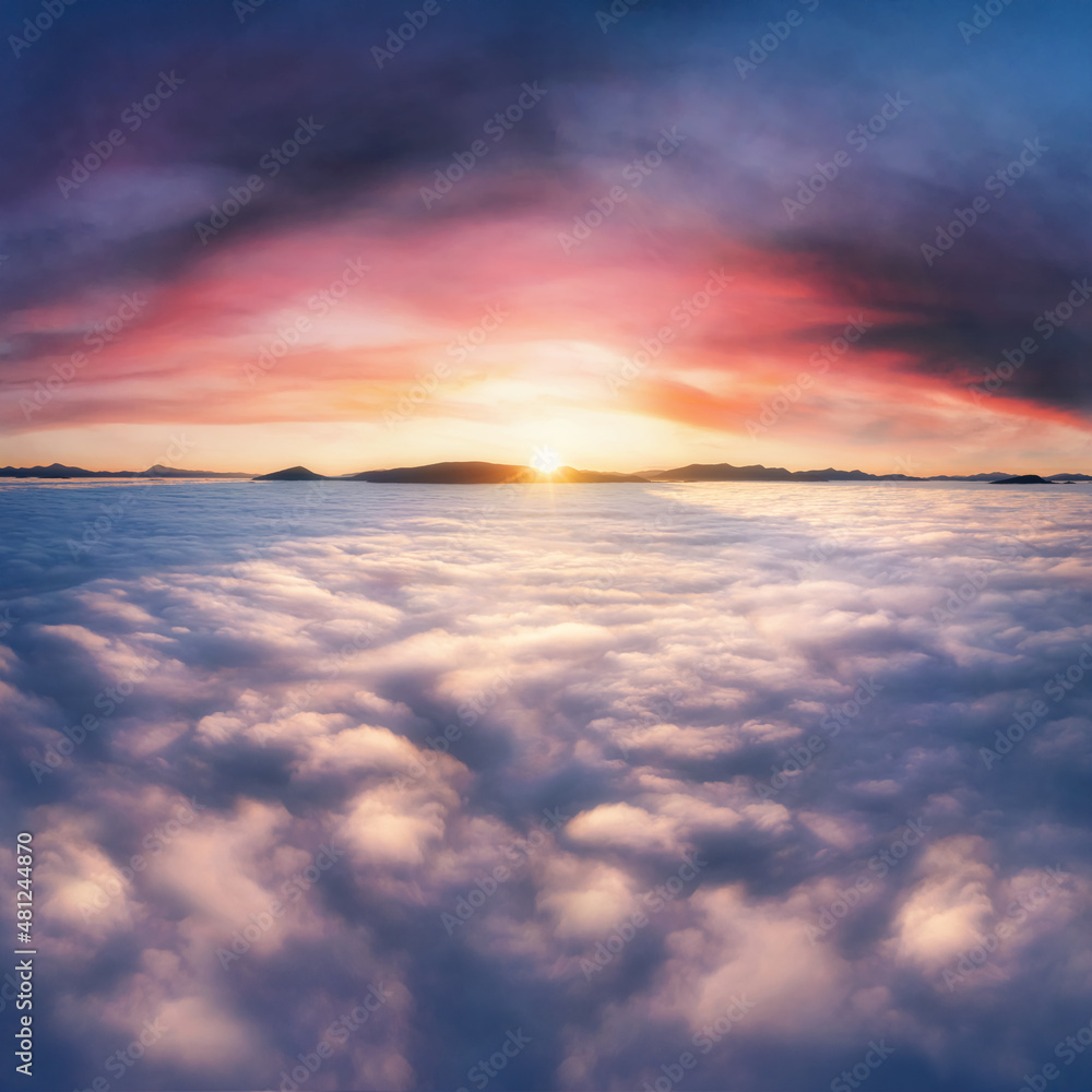 Thick clouds in the mountains at dawn. Beautiful aerial landscape with thick fog against dramatic sunset sky.