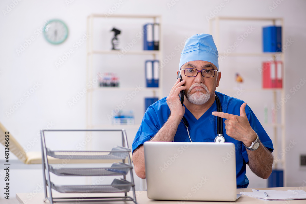 Old male doctor working in the clinic Old male doctor working in the clinic