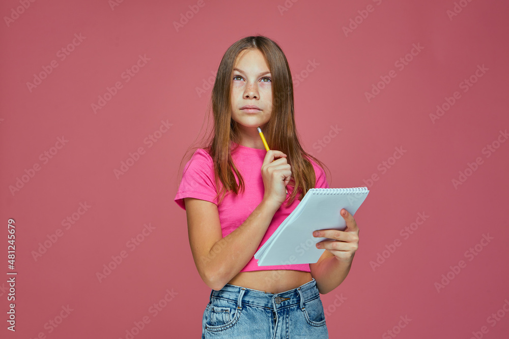 Thoughtful child girl with notebook create ideas, decide task on pink background. Education, back to school concept Thoughtful child girl with notebook create ideas, decide task on pink background. Education, back to school concept