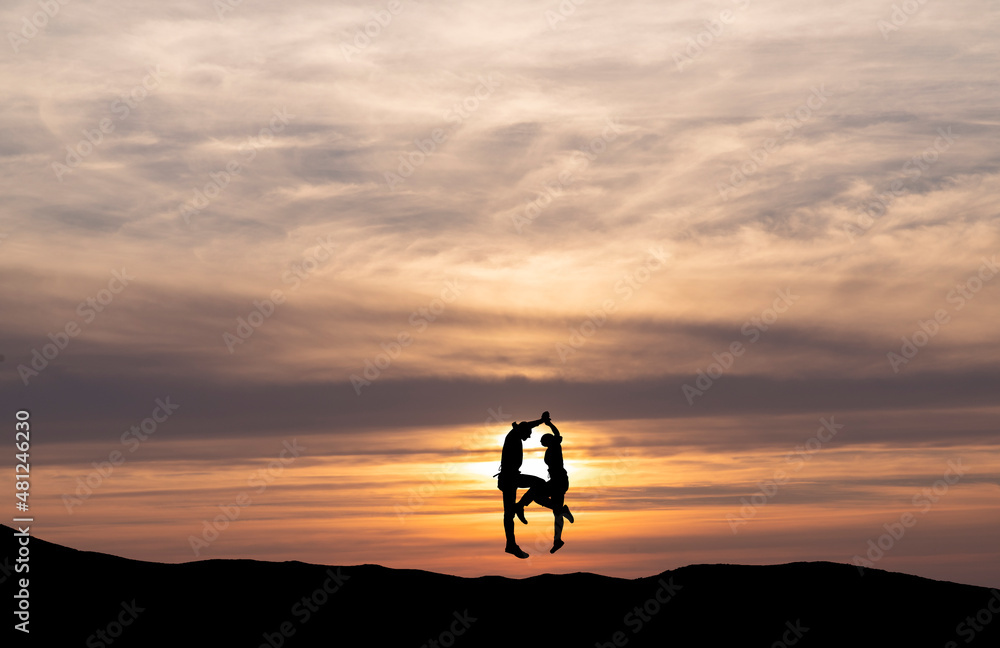 Silhouettes of people at sunset. A couple in love is dancing at sunset.