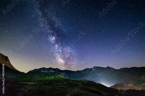 the Milky way galaxy and stars over the Italian French Alps. Night sky on majestic snowcapped mountains and glaciers. Meteor shower on the right