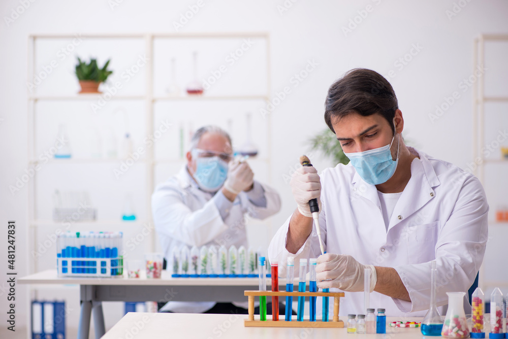 Two male chemists in drugs synthesis concept at the lab Two male chemists in drugs synthesis concept at the lab