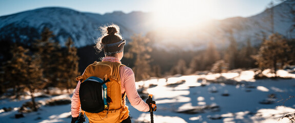 Mountaineer backcountry ski walking ski alpinist in the mountains. Ski touring in alpine landscape with snowy trees. Adventure winter sport.
