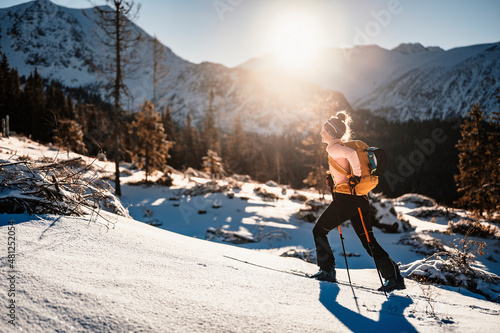 Mountaineer backcountry ski walking ski alpinist in the mountains. Ski touring in alpine landscape with snowy trees. Adventure winter sport. photo