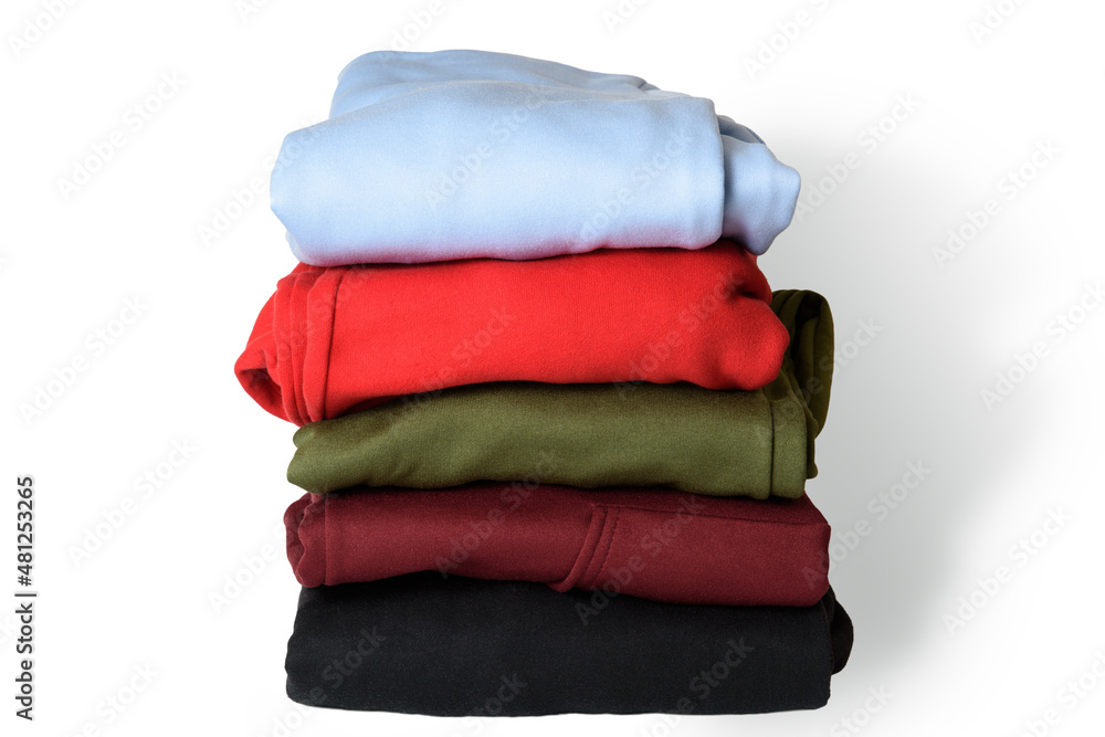 Stack of folded hoodie and hooded sweatshirts on white background. Trendy comfortable casual clothes. Closeup.