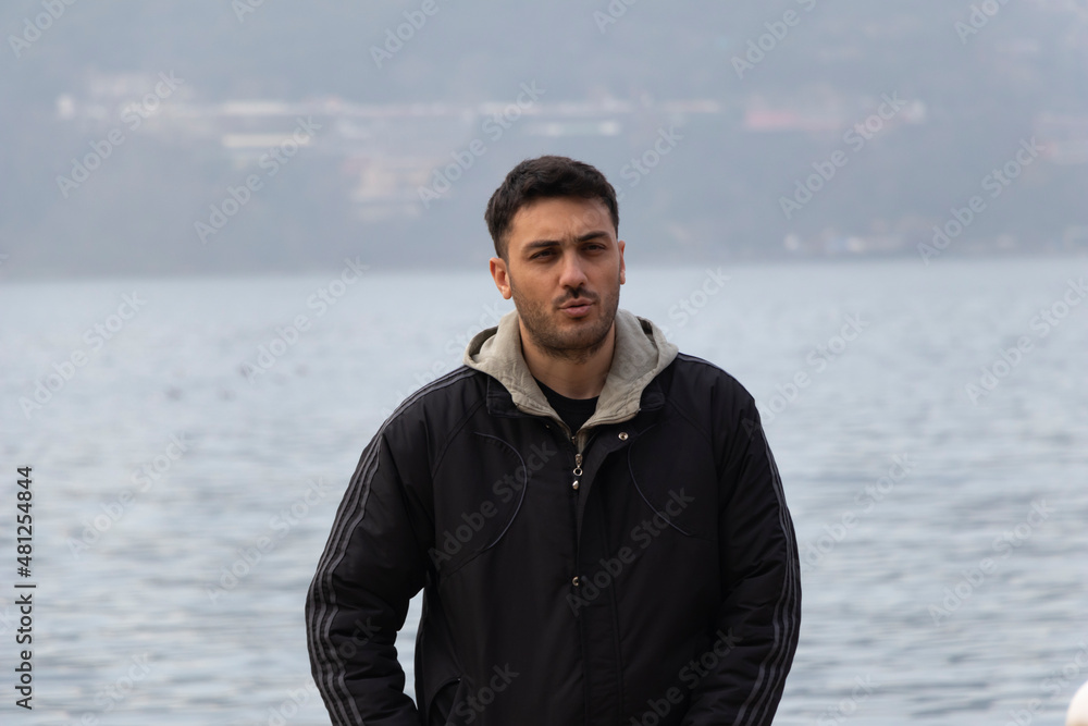 Young boy is talking. He is serious. It's like he's arguing with someone. Sea background. Cold weather. Beautiful view. Winter clothes. Young boy is talking. He is serious. It's like he's arguing with someone. Sea background. Cold weather. Beautiful view. Winter clothes.