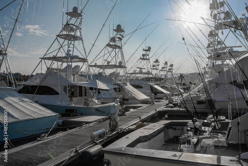 White boats for recreation and fishing in the marine parking lot illuminated by the bright sun. © okyela