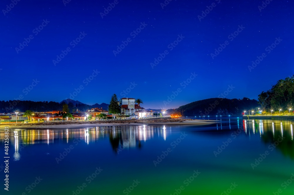 Entrance to the port of Ribadesella, with Santa Marina beach in the background, on a starry night.