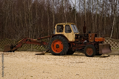 Stara, czerwona koparka -spychacz , stojąca na żwirowym podłożu . An old, red excavator - bulldozer, standing on a gravel ground. 
