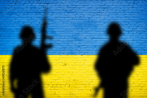 Flag of Ukraine painted on a brick wall with soldiers shadows. Relationship between Ukraine and Russia