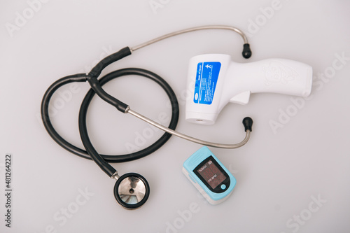 Stethoscope, pulse oximeter and thermometer gun on white background. Treatment of cold or flu. Phonendoscope. Infrared isometric thermometer gun to check body temperature for virus symptoms