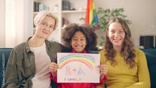Cheerful adopted girl showing family picture, happy lgbt couple proud of child photo