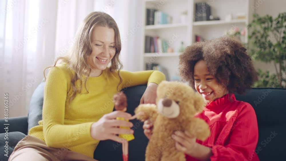 Caucasian mother and black little girl playing with toys, having fun together Caucasian mother and black little girl playing with toys, having fun together