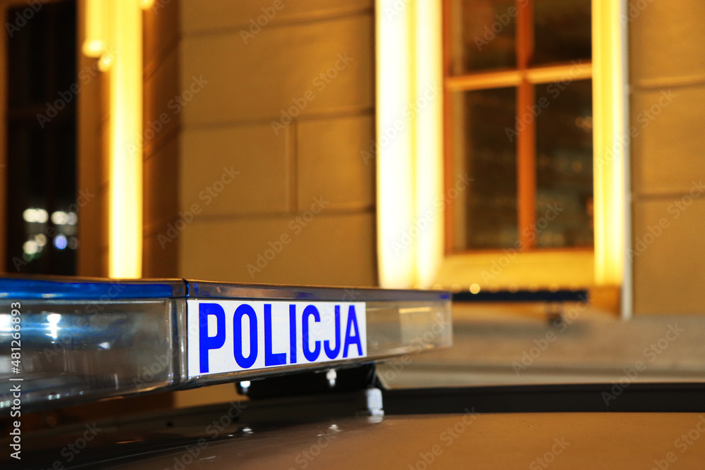 Sygnalizator błyskowy niebieski na dachu radiowozu policji polskiej w nocy na drodze.  - obrazy, fototapety, plakaty 
