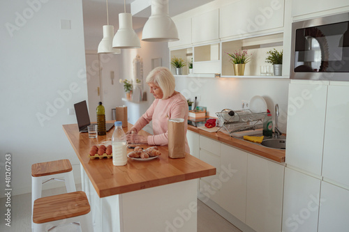 Senior woman is preparing meal in kitchen