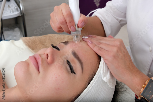 Facial treatment that allows women to rejuvenate. Dermatologist applies a facial treatment to a young white woman, who is lying in a clinic specializing in skin rejuvenation.