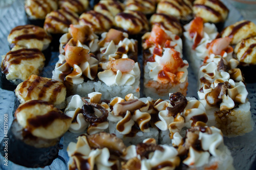 different sushi and rolls. baked sushi with various sauces. tasty food.