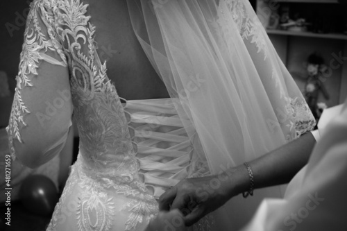 the bride is helped to put on her wedding dress. Corset lacing. wedding preparations. black and white photo.