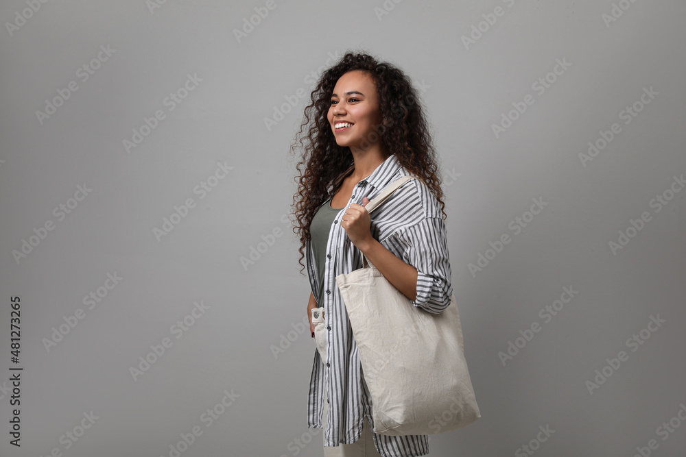 Happy African-American woman with eco bag on grey background. Space for text Happy African-American woman with eco bag on grey background. Space for text