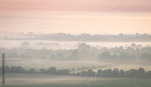 Misty view from Chilterns over oxfordshire at dawn sunrise with soft colours and layers photo
