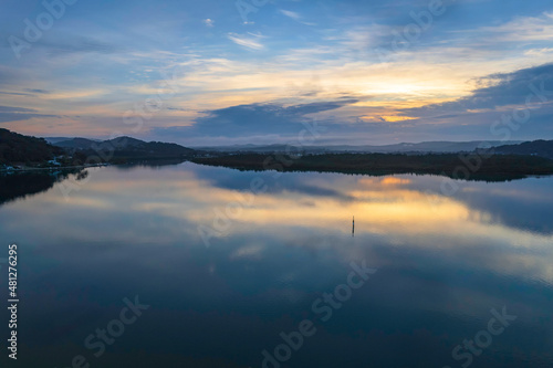 Soft and peaceful sunrise aerial waterscape with clouds and reflections