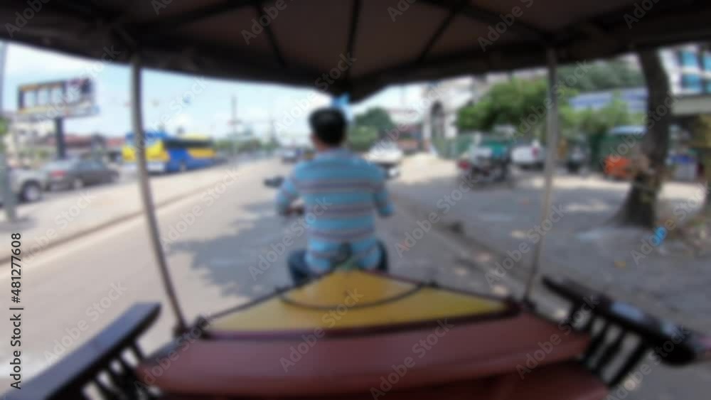 Blurred defocused POV of a tourist in a tuk tuk in Siem Reap driving through its streets. A local taxi takes tourists through the streets of Cambodia a Southeast Asian city Blurred defocused POV of a tourist in a tuk tuk in Siem Reap driving through its streets. A local taxi takes tourists through the streets of Cambodia a Southeast Asian city
