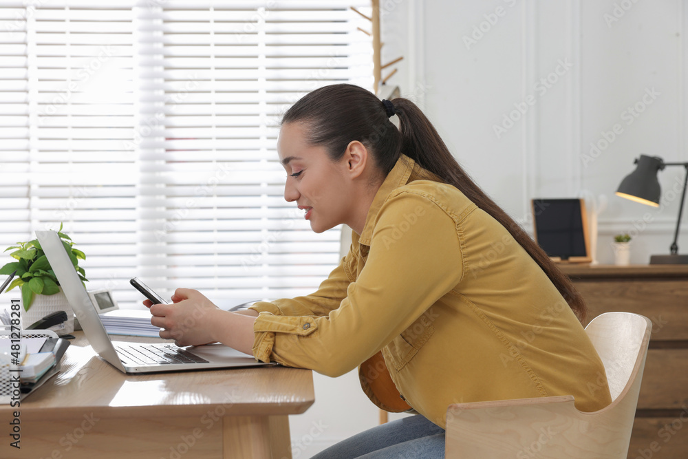 Young woman with poor posture using smartphone at table indoors Young woman with poor posture using smartphone at table indoors