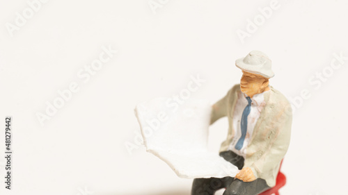 椅子に座って新聞を読む老人の人形