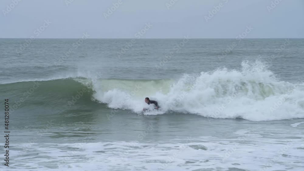 Bodyboarder surfing ocean wave on a cloudy winter day. Bodyboarder surfing ocean wave on a cloudy winter day.