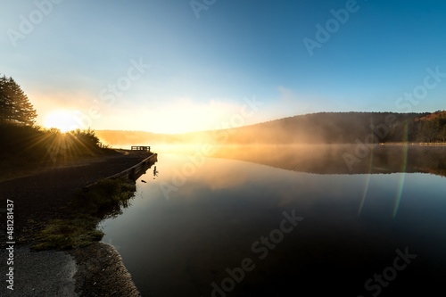 Spruce Knob lake blue sky water in West Virginia mountains fall autumn fog mist sunrise morning glowing yellow sunlight sun flare rays beams in Monongahela National Forest