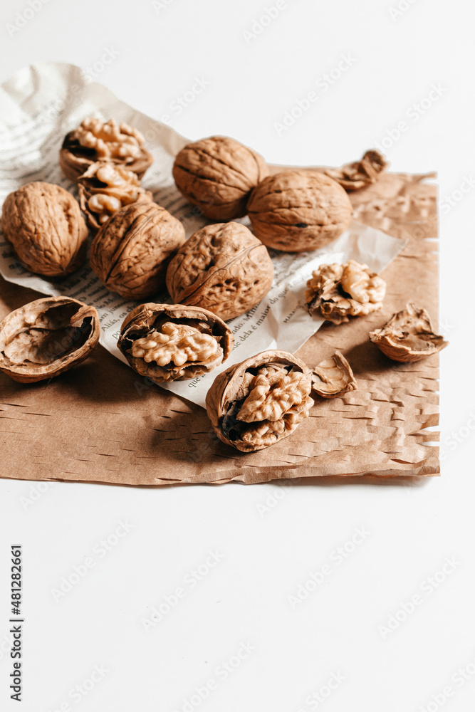 Cosy autumn aesthetic composition with dry  leaves, walnuts on white background. Flat lay, top view, copy space.