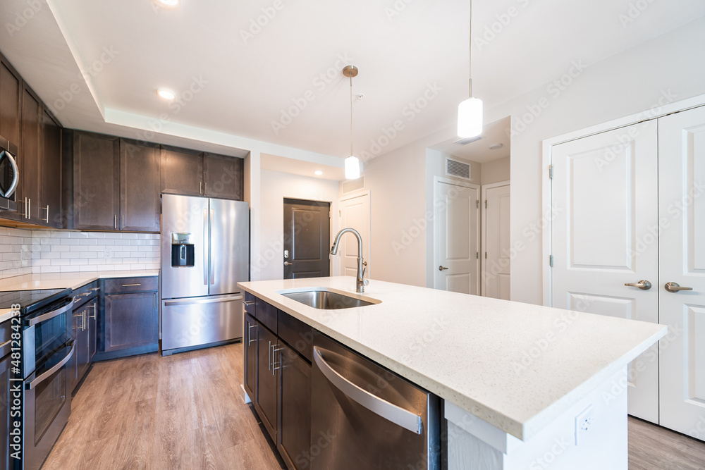Empty vacant kitchen open plan modern apartment with sink faucet quartz countertop island by new French door fridge refrigerator wood cabinets and recessed ceiling lamp lights - obrazy, fototapety, plakaty 