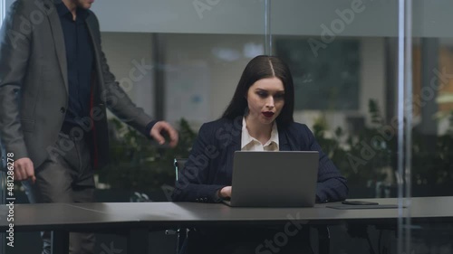 Young lady working on laptop at office, lustful man boss touching her shoulder, angry woman pushing him away photo