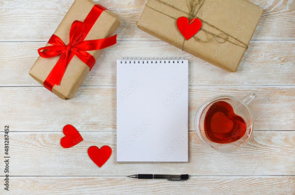 Valentine's Day background and eco friendly Gifts in craft paper with Red Ribbon, Wooden Heart Shaped Decoration Festive Flat lay, zero waste presents top view with sheet paper and pen Valentine's Day background and eco friendly Gifts in craft paper with Red Ribbon, Wooden Heart Shaped Decoration Festive Flat lay, zero waste presents top view with sheet paper and pen