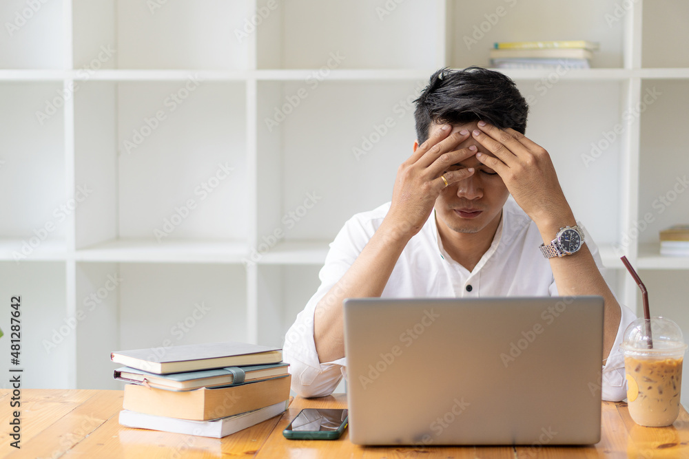A young man sits down at work with a laptop and a coffee mug with tiger skins and a smartphone. A young man sits down at work with a laptop and a coffee mug with tiger skins and a smartphone.