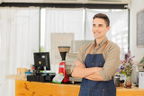 Young man cafe owner standing in front of the shop smiling happily, food and drink concept.
