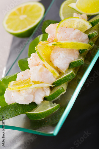 Close up of ceviche from alaska pollock on a glass plate with lime and herbs