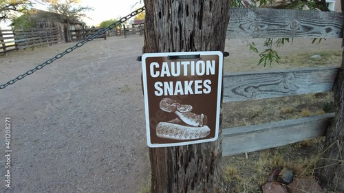 Caution snakes warning sign on wooden post on a ranch in Arizona