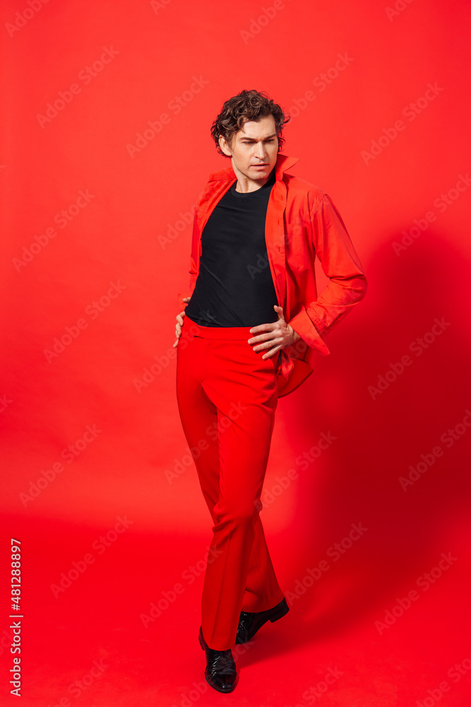 Tall handsome man dressed in red shirt posing on the red background Tall handsome man dressed in red shirt posing on the red background