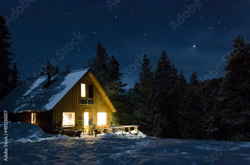 Starry skies over a cabin at night in the snowy mountains © Brian