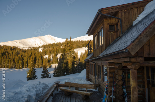 Sun hits the mountains next to a cabin in the snow © Brian