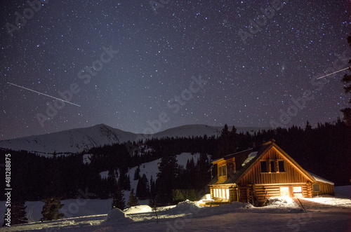 Starry skies over a cabin at night in the snowy mountains