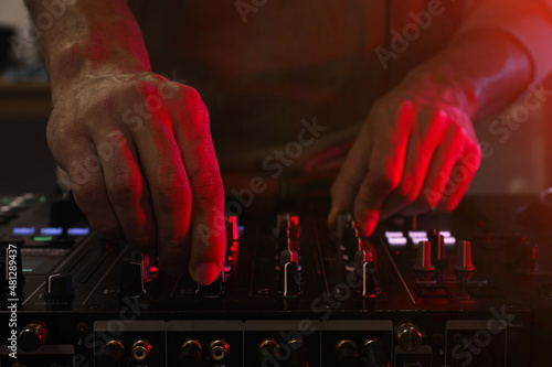 Obraz na plátně DJ creating music on modern console mixer in night club, closeup