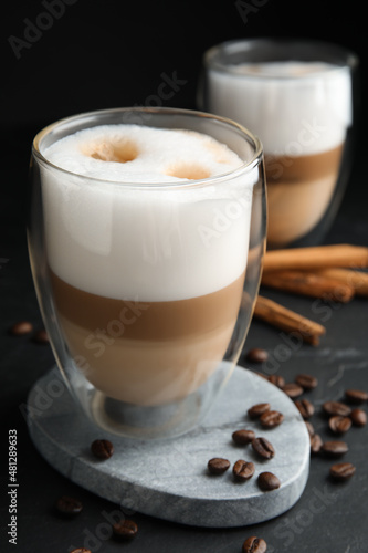 Fototapeta Naklejka Na Ścianę i Meble -  Delicious latte macchiato, cinnamon sticks and coffee beans on black table
